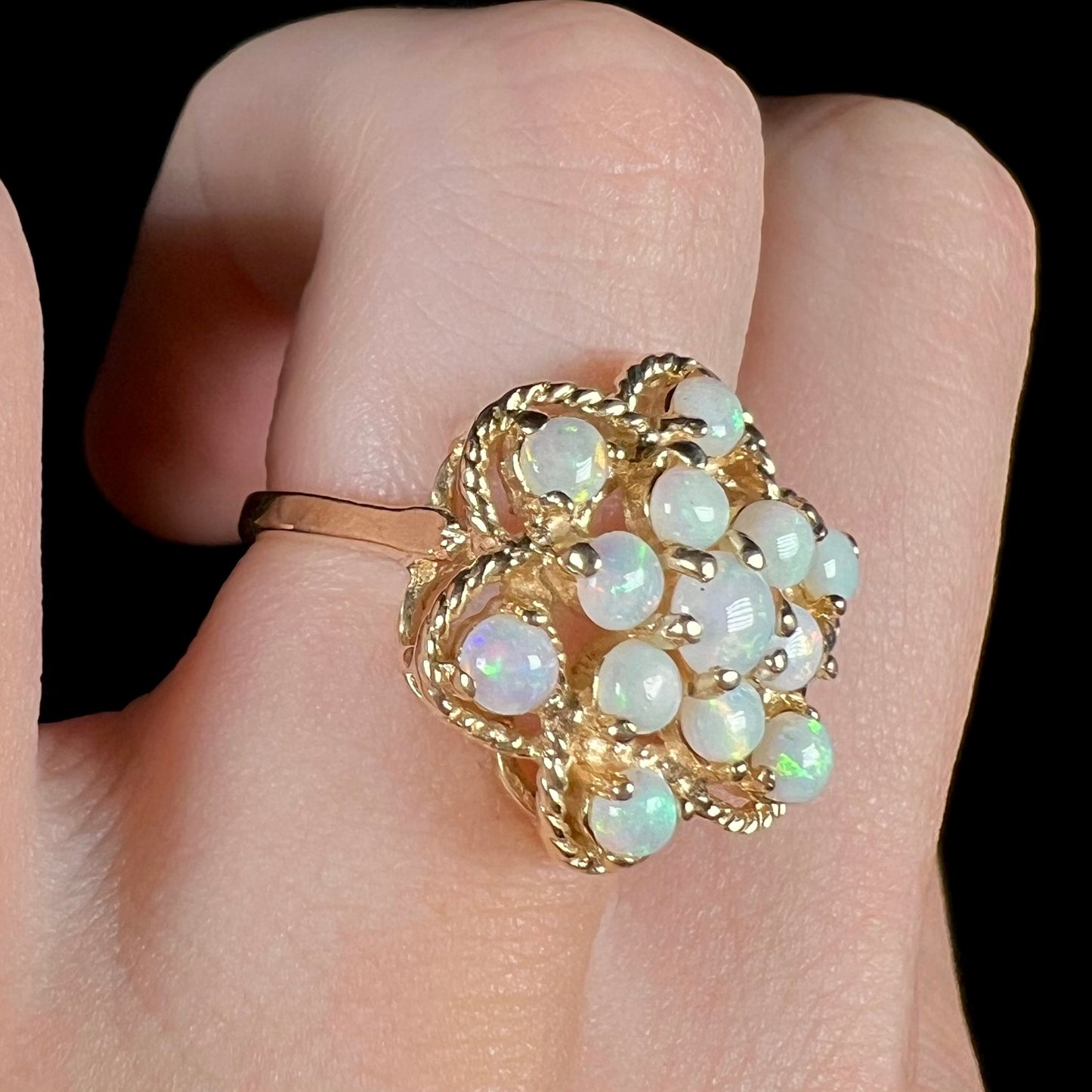 Angled close-up of a finger wearing a vintage Australian opal atomic-style cluster ring.