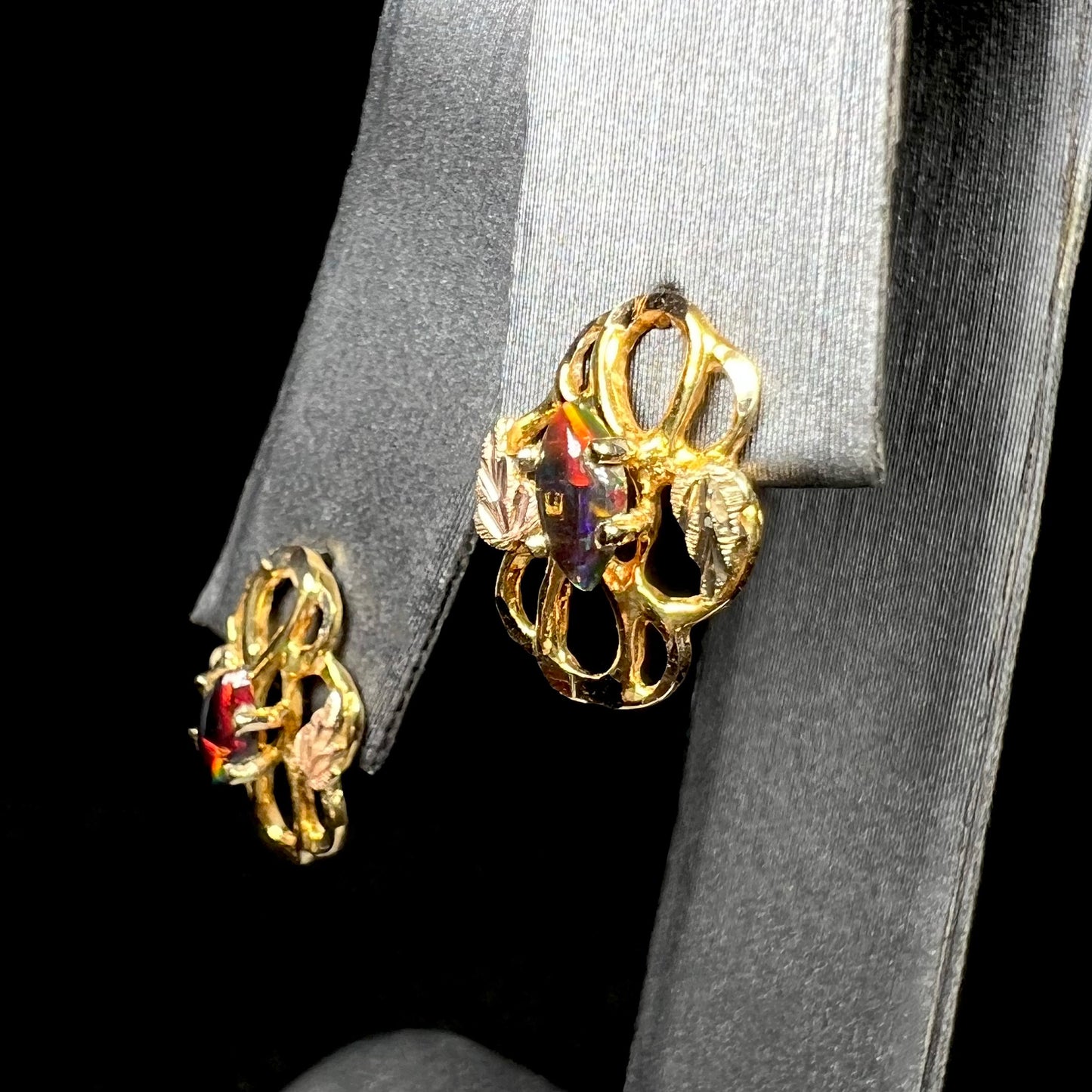 Close-up of vintage Black Hills gold black opal stud earrings on ring display