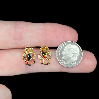 Dime resting on fingers next to pair of vintage Black Hills gold opal stud earrings