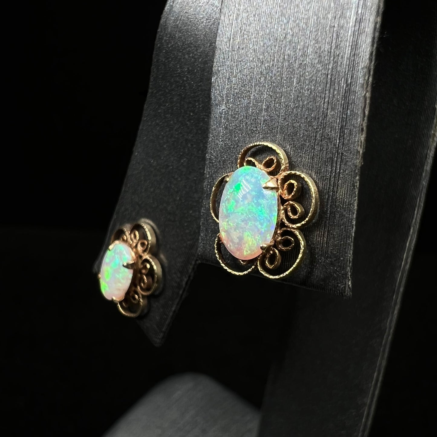 Angled close-up of vintage 1970s opal stud earrings with flower design on earring display