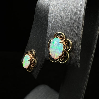 Angled close-up of vintage 1970s opal stud earrings with flower design on earring display