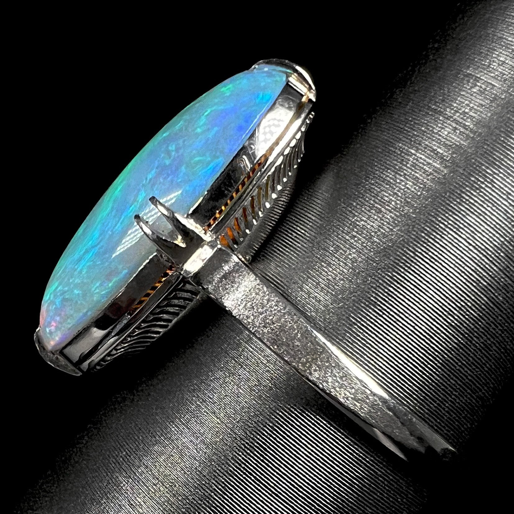 The side view of a vintage crystal opal ring.  The platinum band is textured.