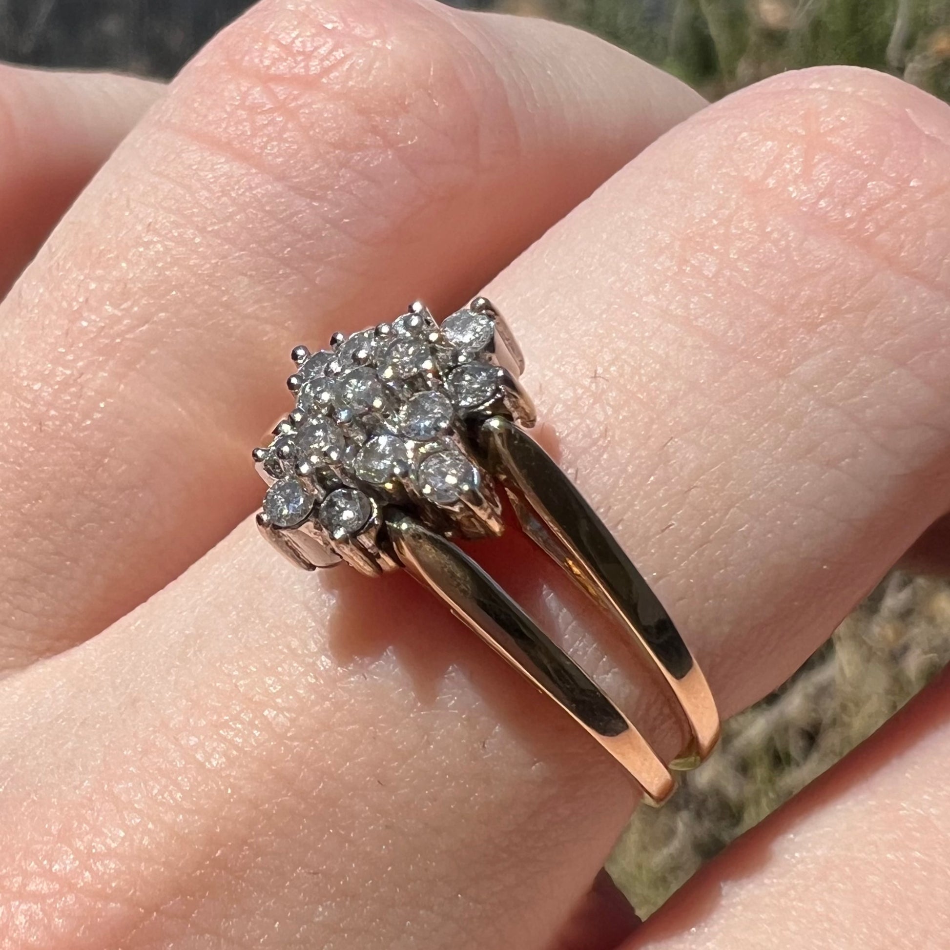 Women's vintage round diamond cluster flip ring, worn on finger in sunlight