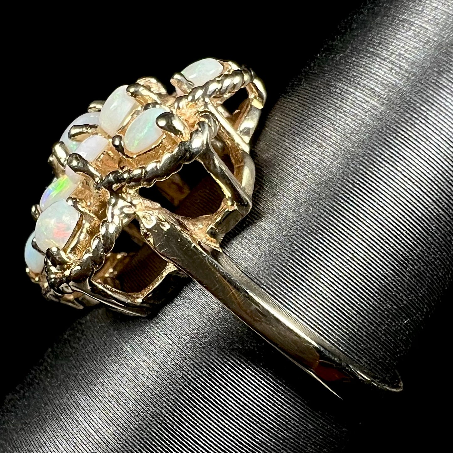 Side view of a vintage yellow gold cluster ring with an atomic motif, shown on a ring display, focused on the ring's shank.