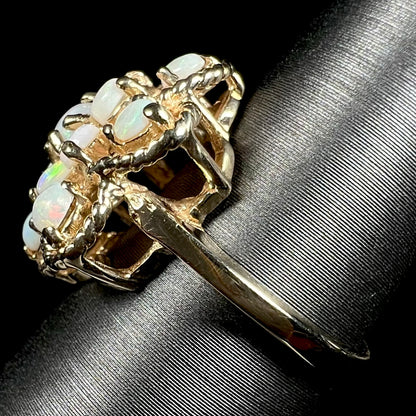 Side view of a vintage yellow gold cluster ring with an atomic motif, shown on a ring display, focused on the ring's shank.