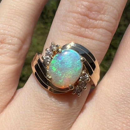 Close-up of vintage 14k gold Australian semi-crystal opal and diamond accented ring worn on finger in sunlight