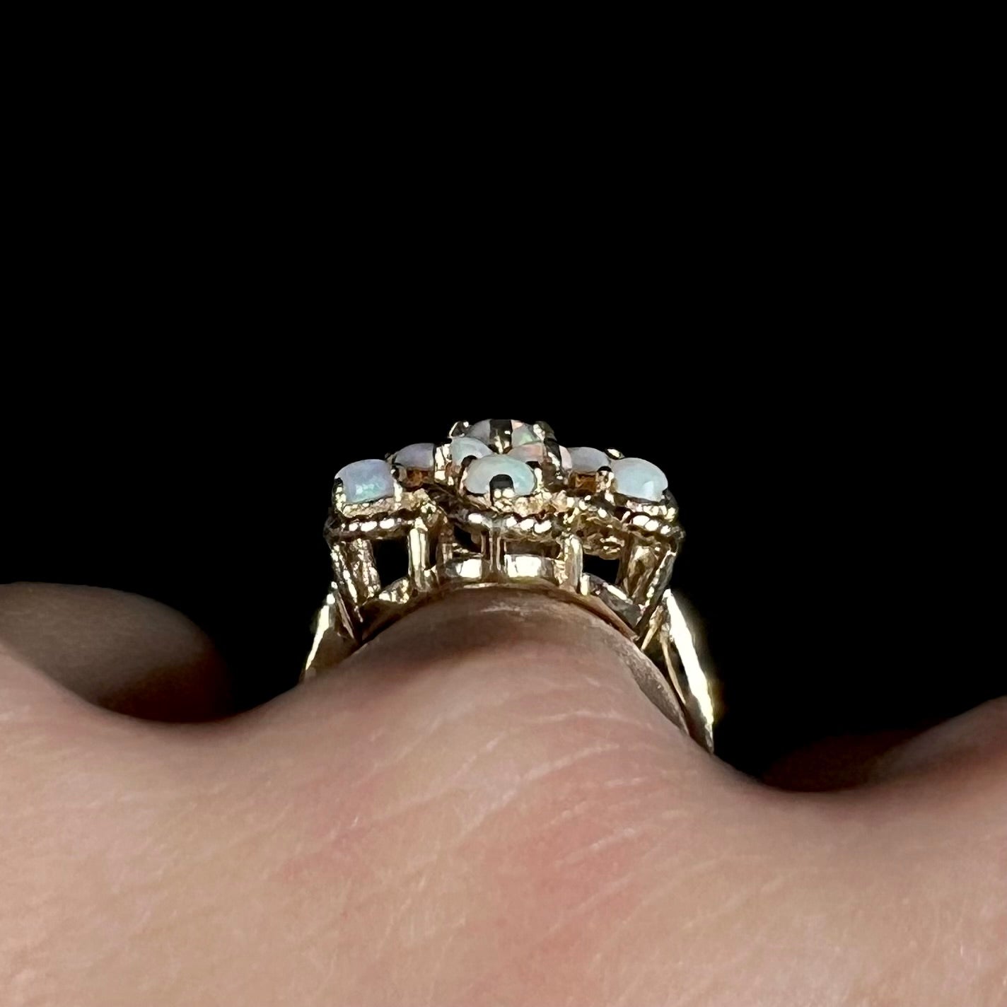 Gallery view of a vintage, yellow gold opal cluster ring, worn on a finger.
