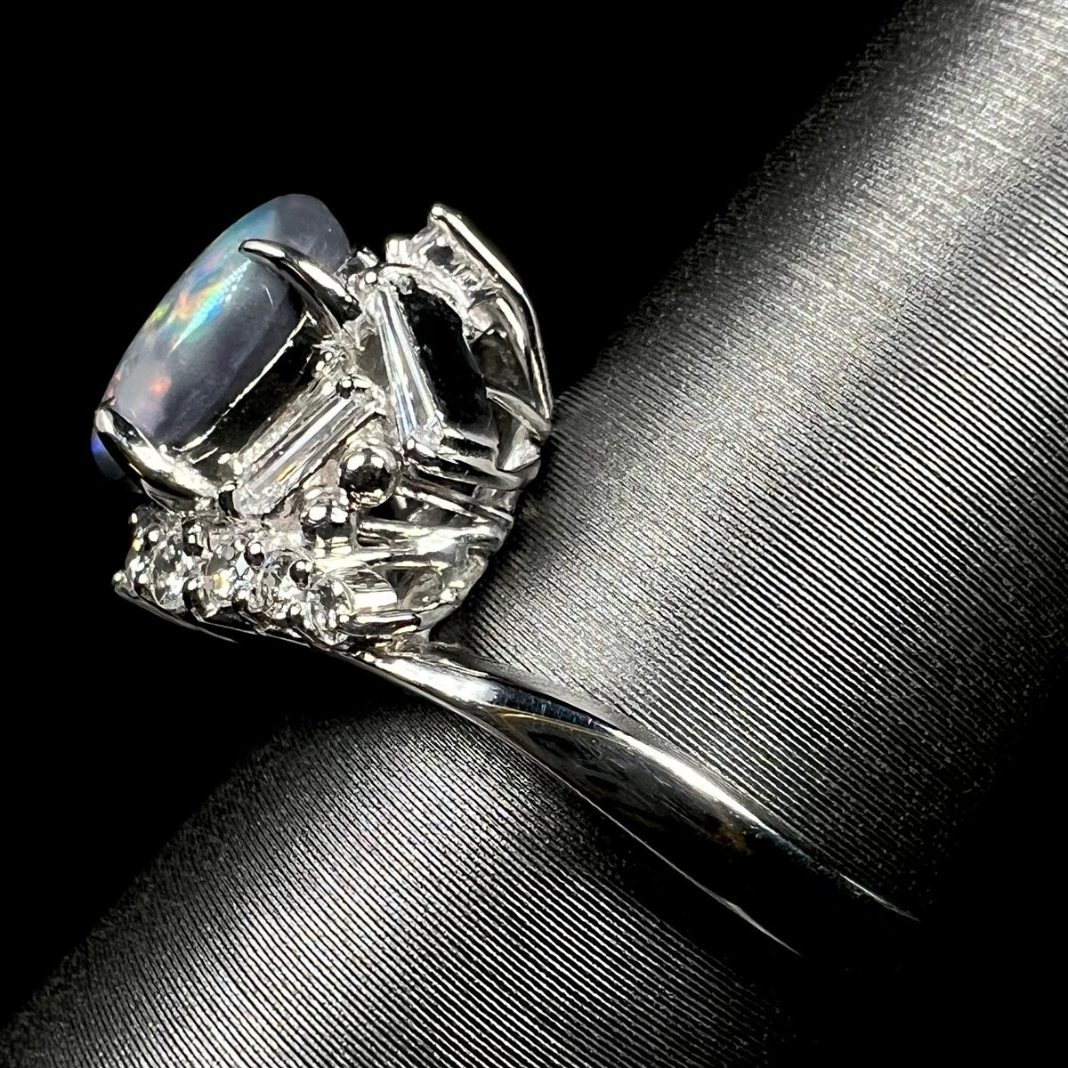 Side view of a vintage Japanese platinum ring set with dark Australian opal and diamond accents.  The ring's polished shank is in view.