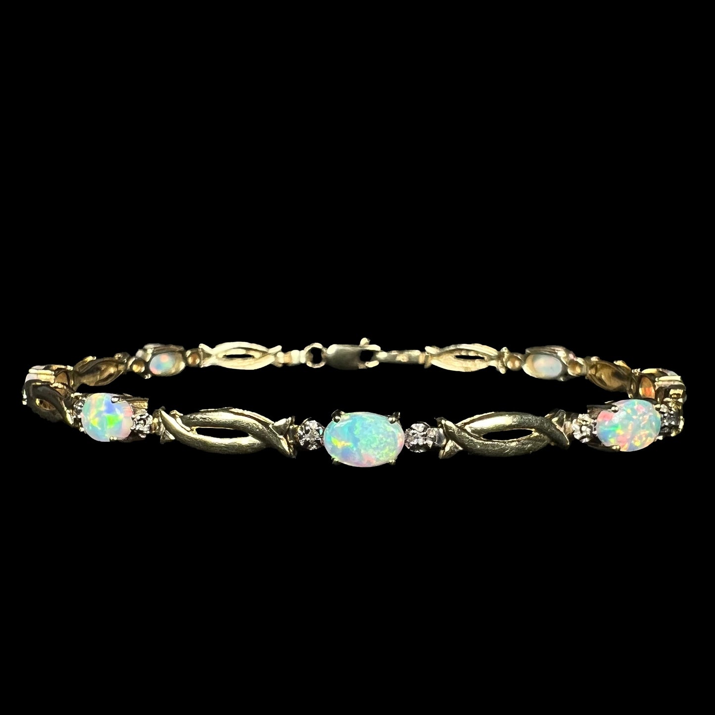 Front view of a vintage 1990s lab-created opal and diamond tennis bracelet in 10k yellow gold with open, modernist style links.