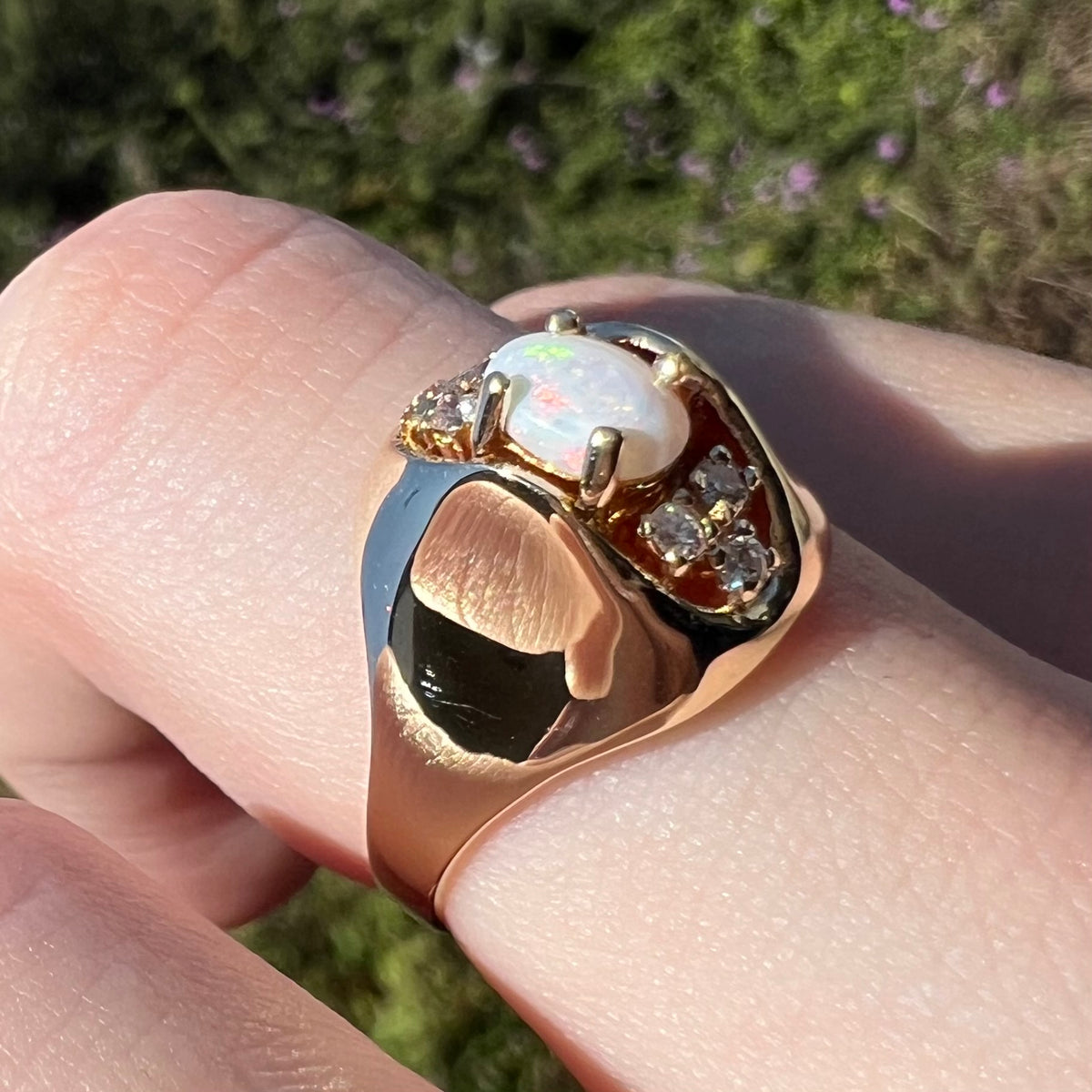 Vintage c.1960s Mid-Century modern opal and diamond ring made from 14k gold shown close-up on finger in sunlight