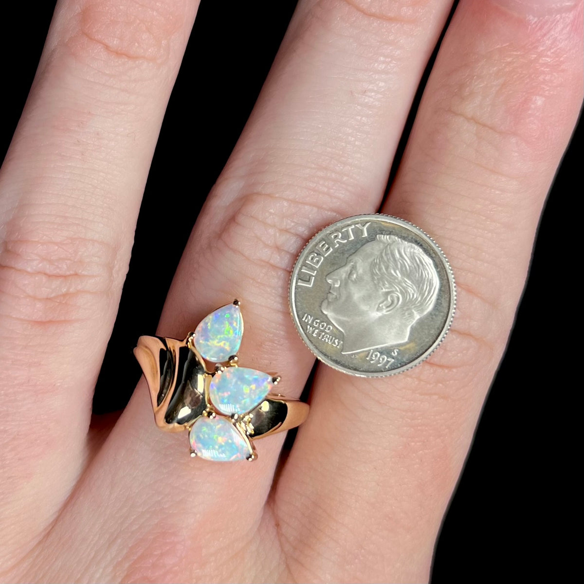 Vintage yellow gold Modernist-style opal ring worn on a hand next to a US dime coin for scale.