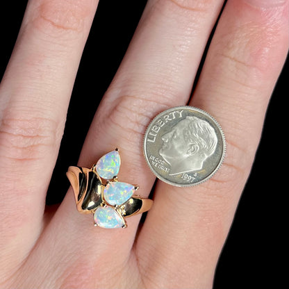 Vintage yellow gold Modernist-style opal ring worn on a hand next to a US dime coin for scale.