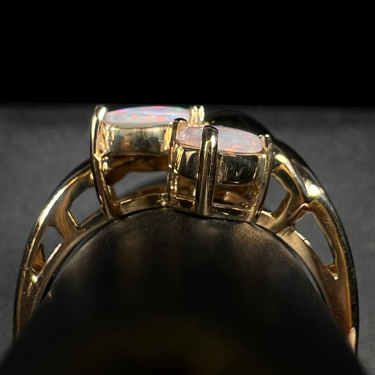 Side gallery view of a vintage, Modernist-style gold opal ring on a ring display.  Two opals are seen.
