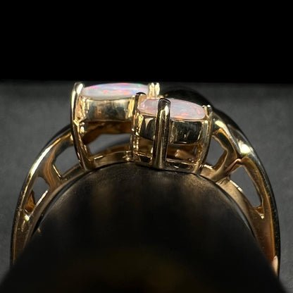 Side gallery view of a vintage, Modernist-style gold opal ring on a ring display.  Two opals are seen.