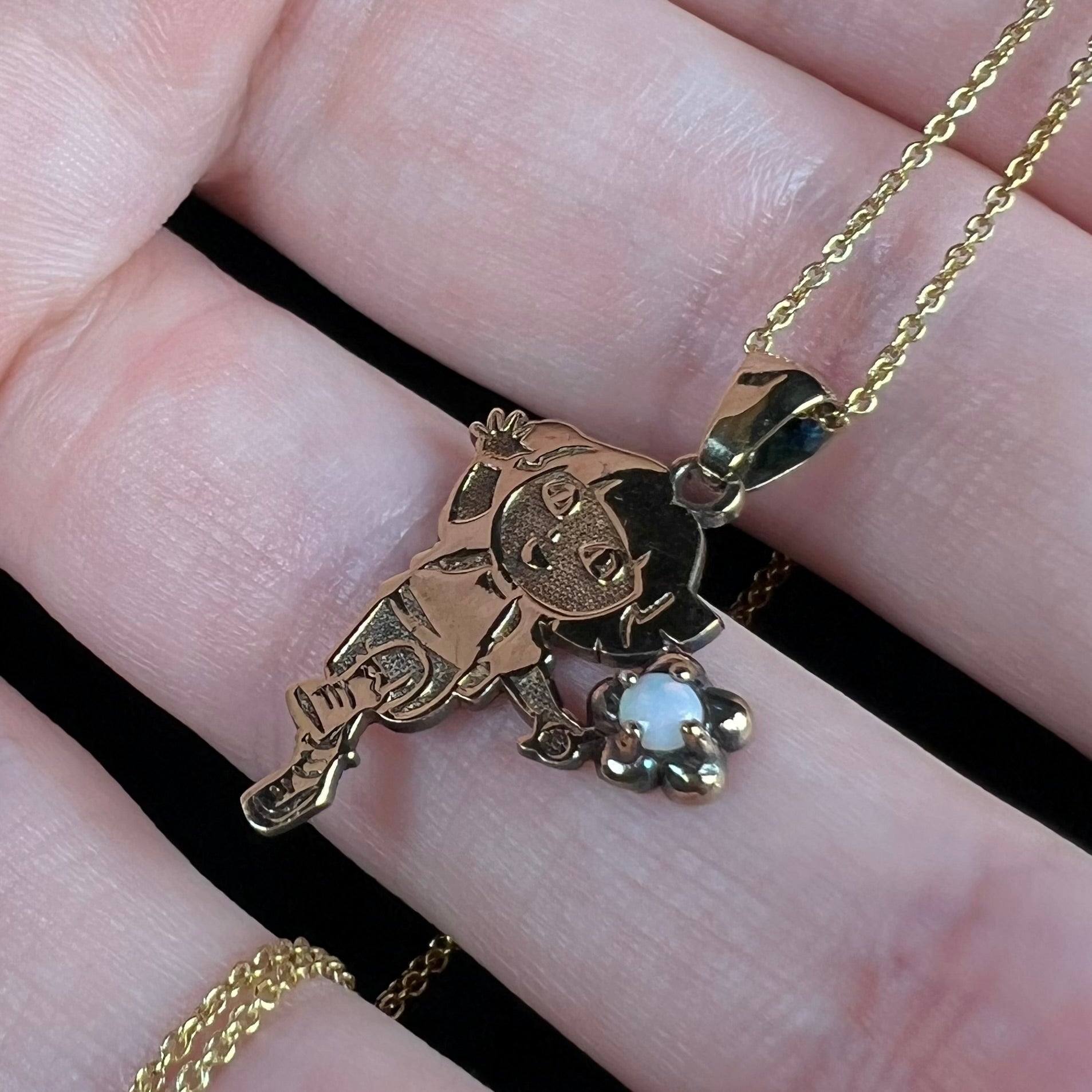 Close-up angled view of vintage Nickelodeon Dora the Explorer opal pendant held in hand.