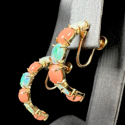 Angled side view of vintage c.1990s opal and coral screw-on clip earrings in 14k gold, shown on earring display