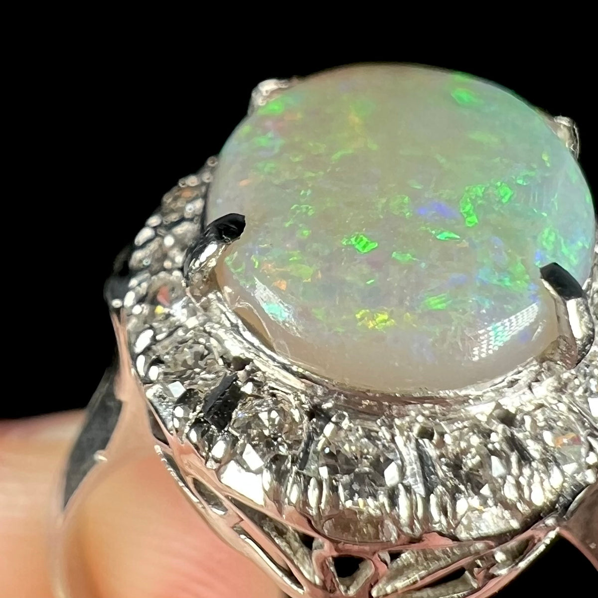 Close-up of the small edge chip beneath one prong on the Australian opal mounted in vintage platinum ring, visible from the side but not face-up.