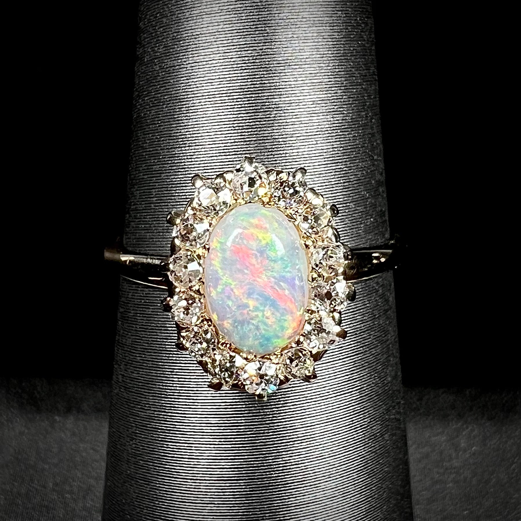 An Edwardian style 18 karat yellow gold opal ring.  The opal is surrounded by a halo of Old European Cut diamonds.