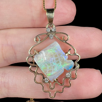 Close-up of vintage 1980s-era carved Australian opal fish pendant with diamond accents representing bubbles, held in hand