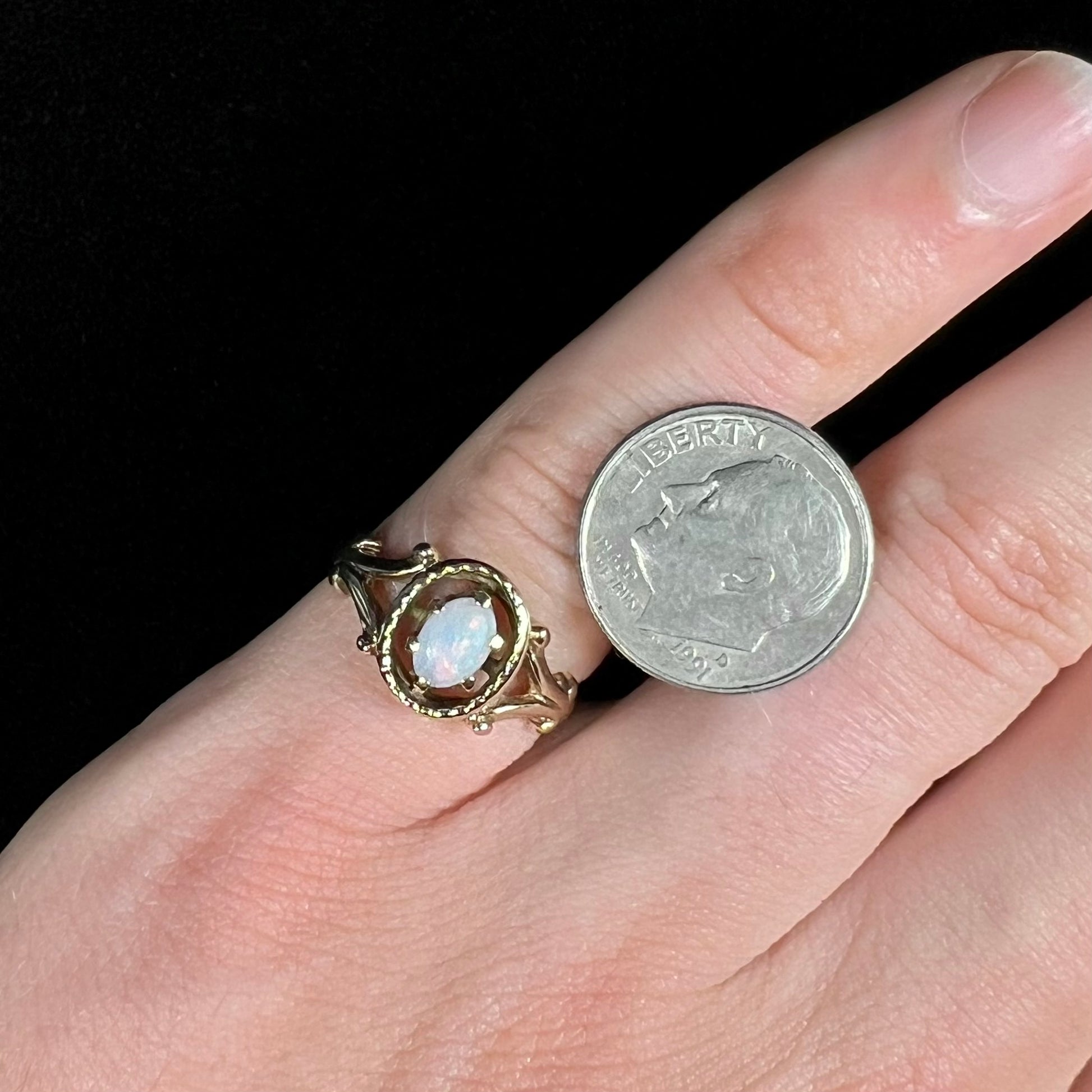 A ladies' Art Nouveau style opal solitaire ring.  The mounting is yellow gold with filigree accents.