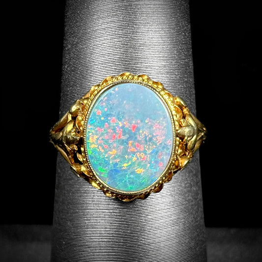 A yellow gold semi-black opal ring with a Victorian fleur-de-lis design.