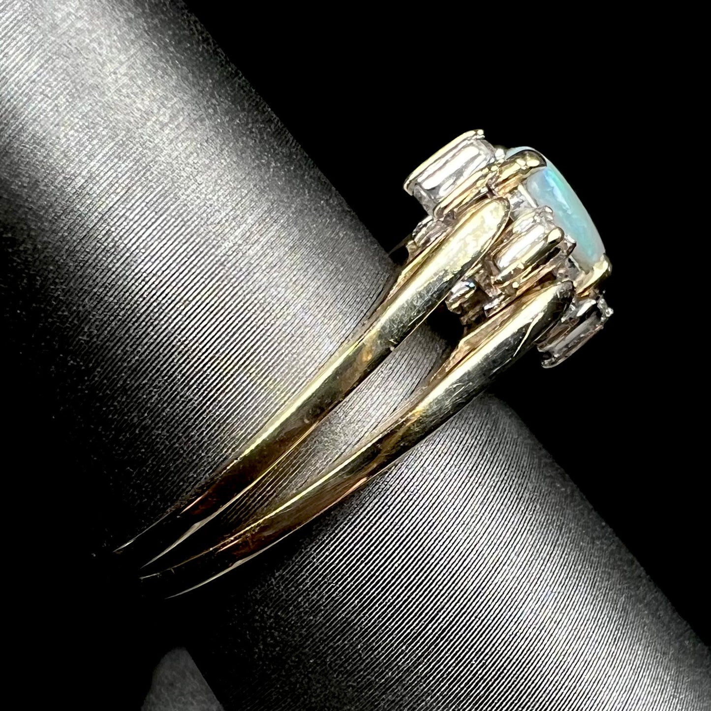 Vintage reversible gold opal and diamond flip ring shown from side view on ring display, the ring's shanks in focus