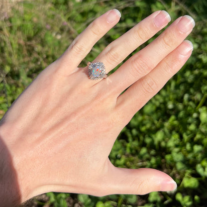 A vintage semi-black opal and diamond ring featuring a Lightning Ridge opal with red colors set in platinum, worn on a hand.