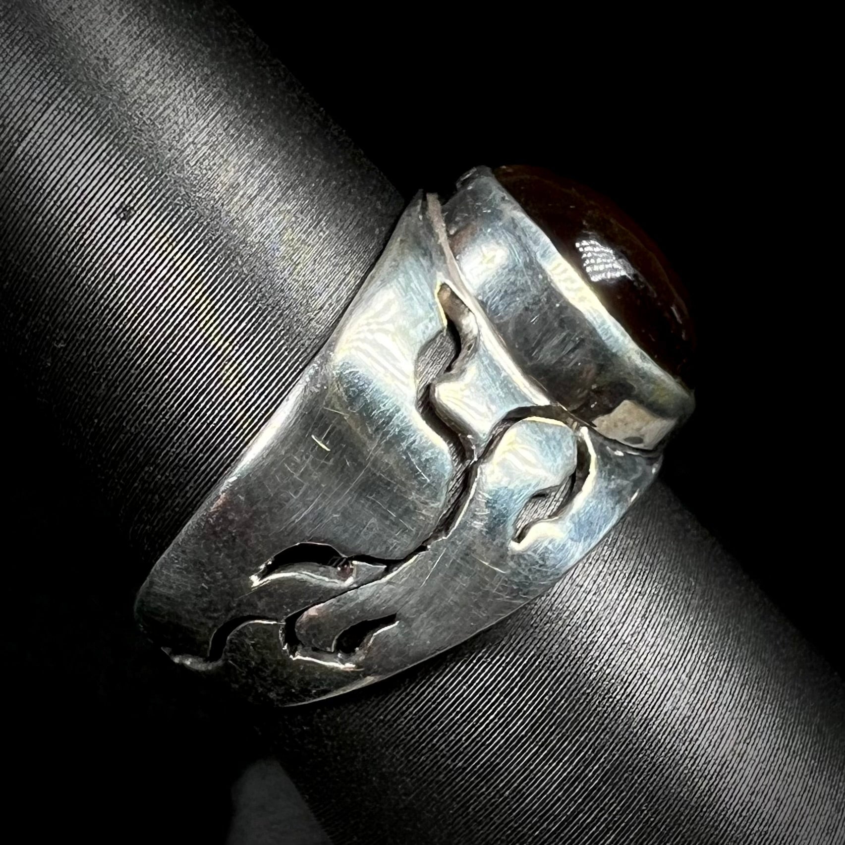 A vintage sterling silver fire agate ring shown from the side profile, displaying its open, vine-like design.