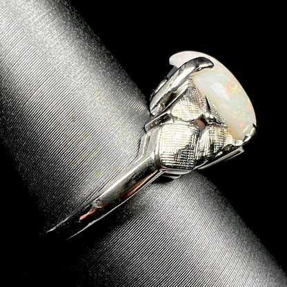 A vintage, textured 14k white gold Australian opal ring on a ring display, shown from the side view, its shank in focus