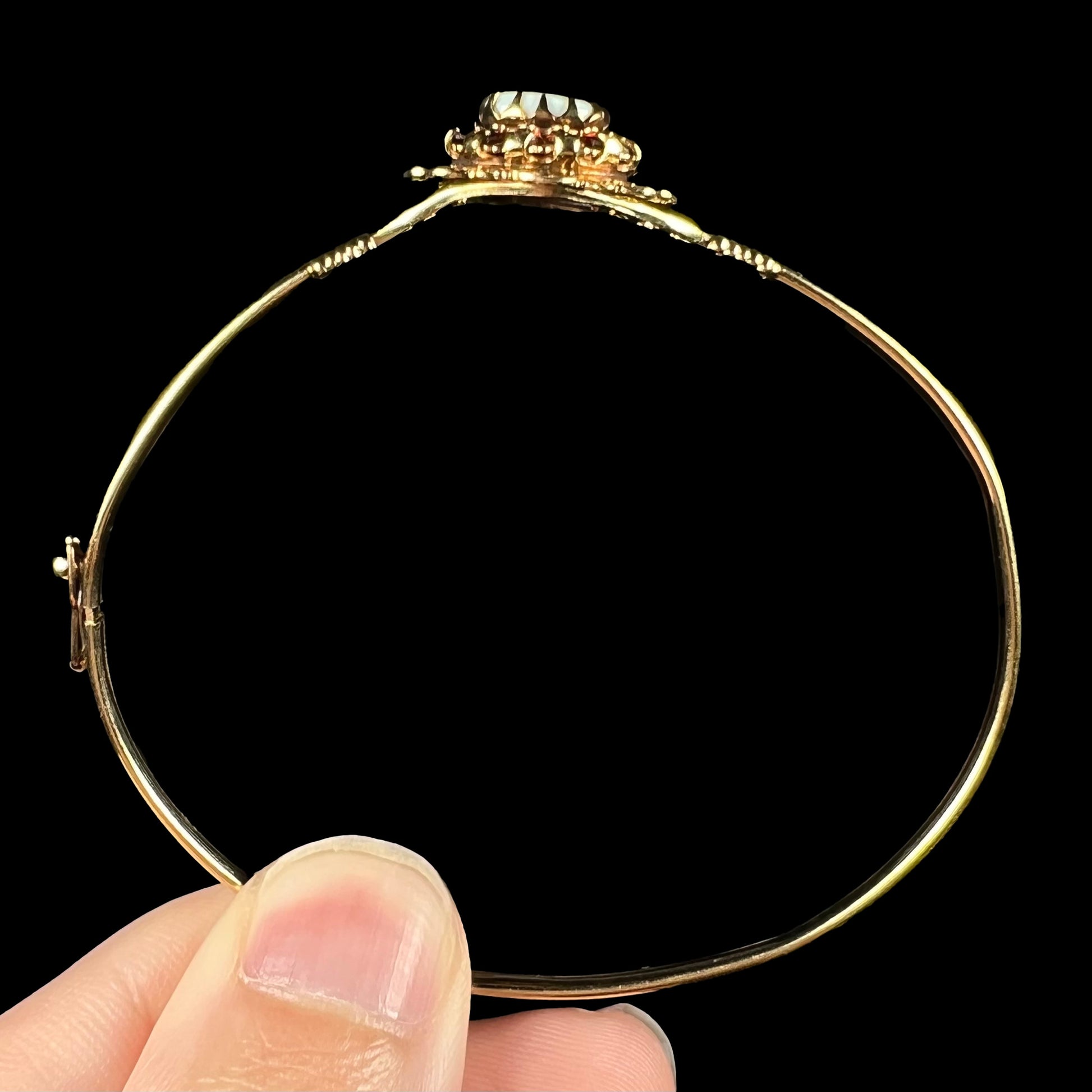 A vintage yellow gold opal bangle bracelet shown from the side gallery view; the top of the bracelet is bent.