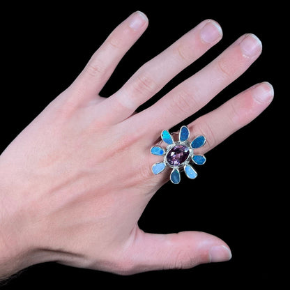 A sterling silver flower shaped ring set with an oval cut amethyst in the center and black opal doublet petals.