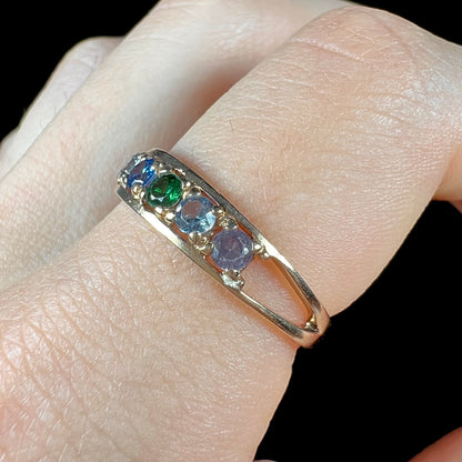 A ladies' yellow gold band set with green, dark blue, light blue, and light purple stones.