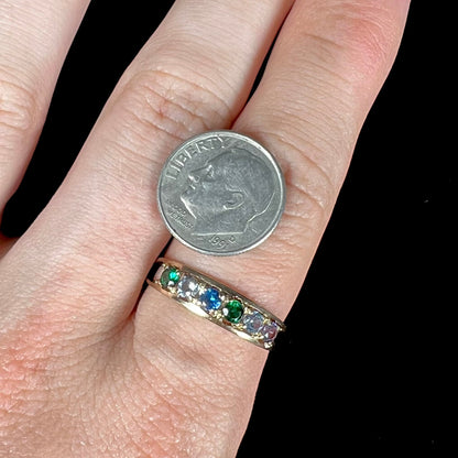 A ladies' yellow gold band set with green, dark blue, light blue, and light purple stones.