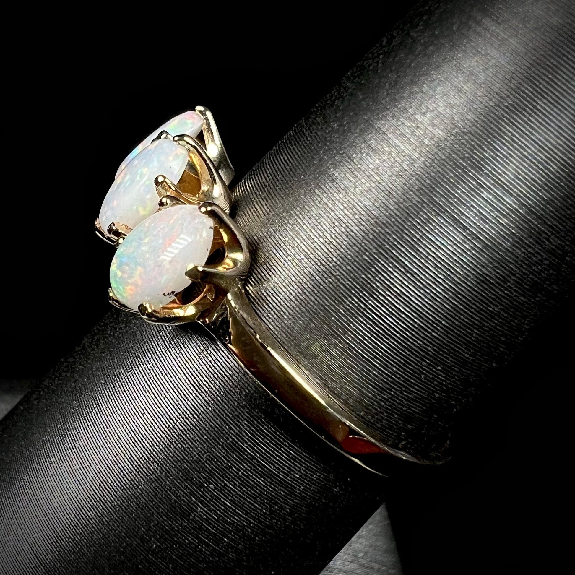 A vintage yellow gold ring mounted with three oval cut white Australian opals.