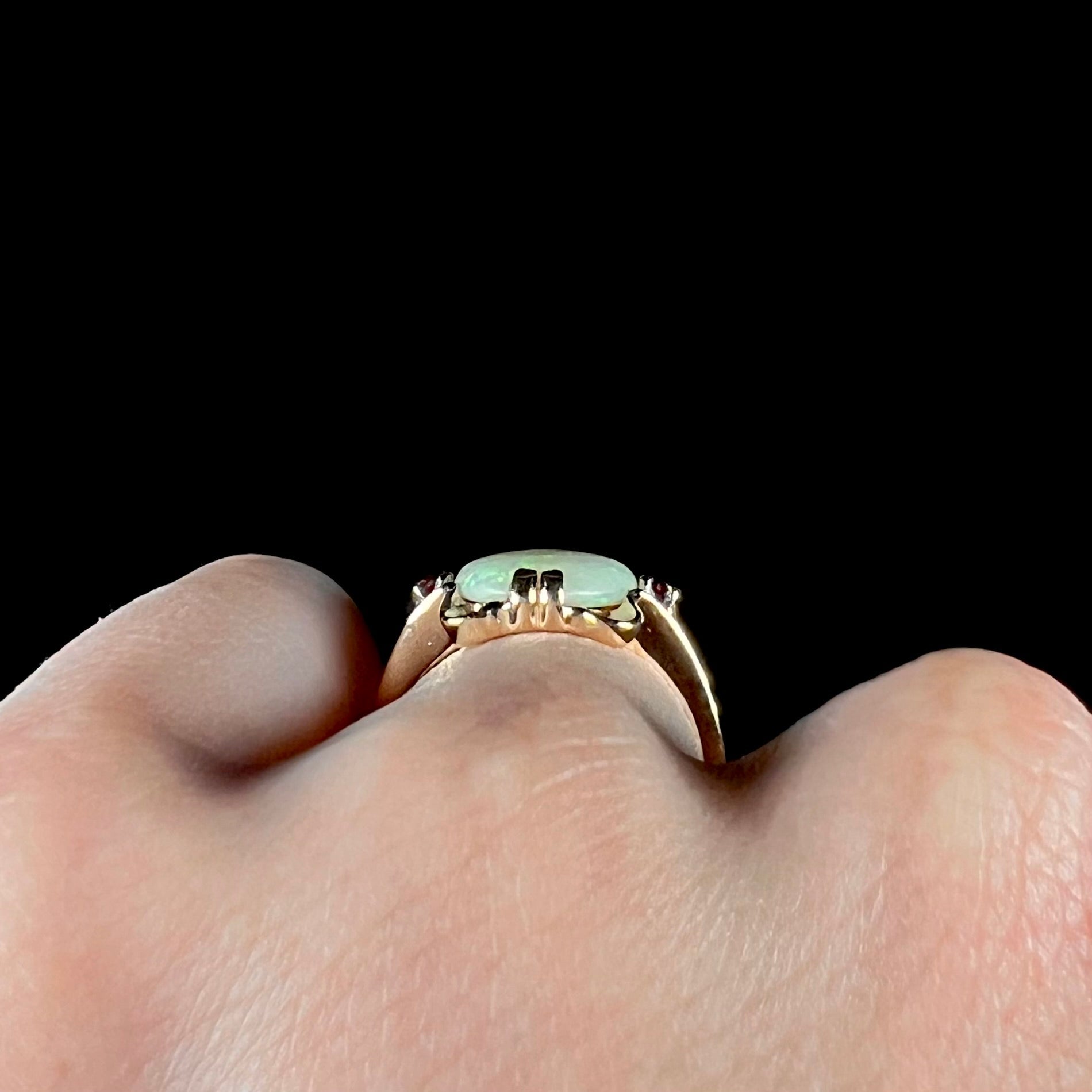 A turn of the century Art Nouveau opal and pink sapphire ring.   The ring is yellow gold and palladium.  The opal is green and purple.