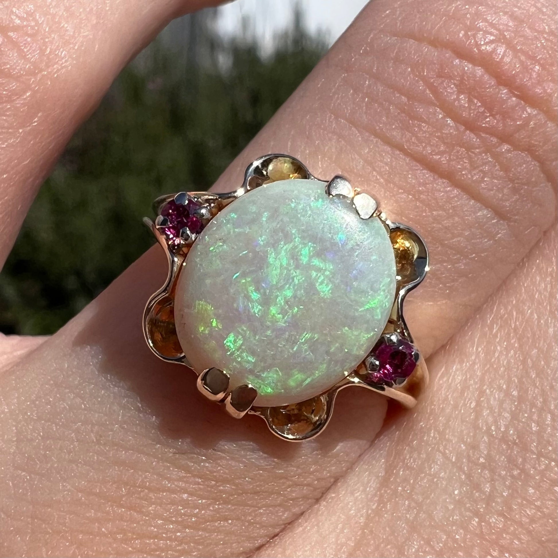 A turn of the century Art Nouveau opal and pink sapphire ring.   The ring is yellow gold and palladium.  The opal is green and purple.