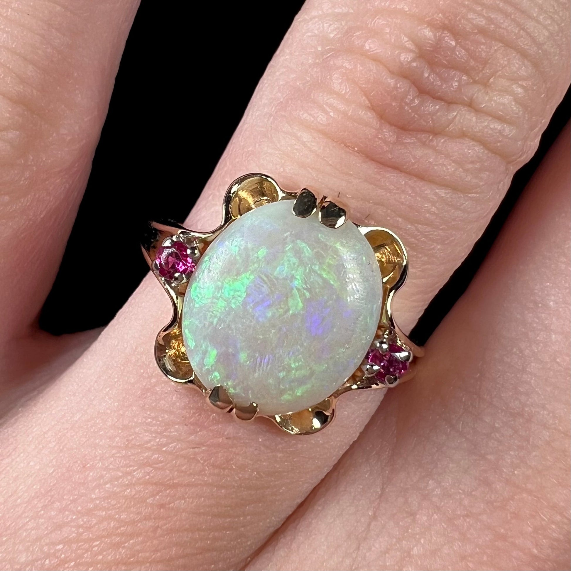 A turn of the century Art Nouveau opal and pink sapphire ring.   The ring is yellow gold and palladium.  The opal is green and purple.