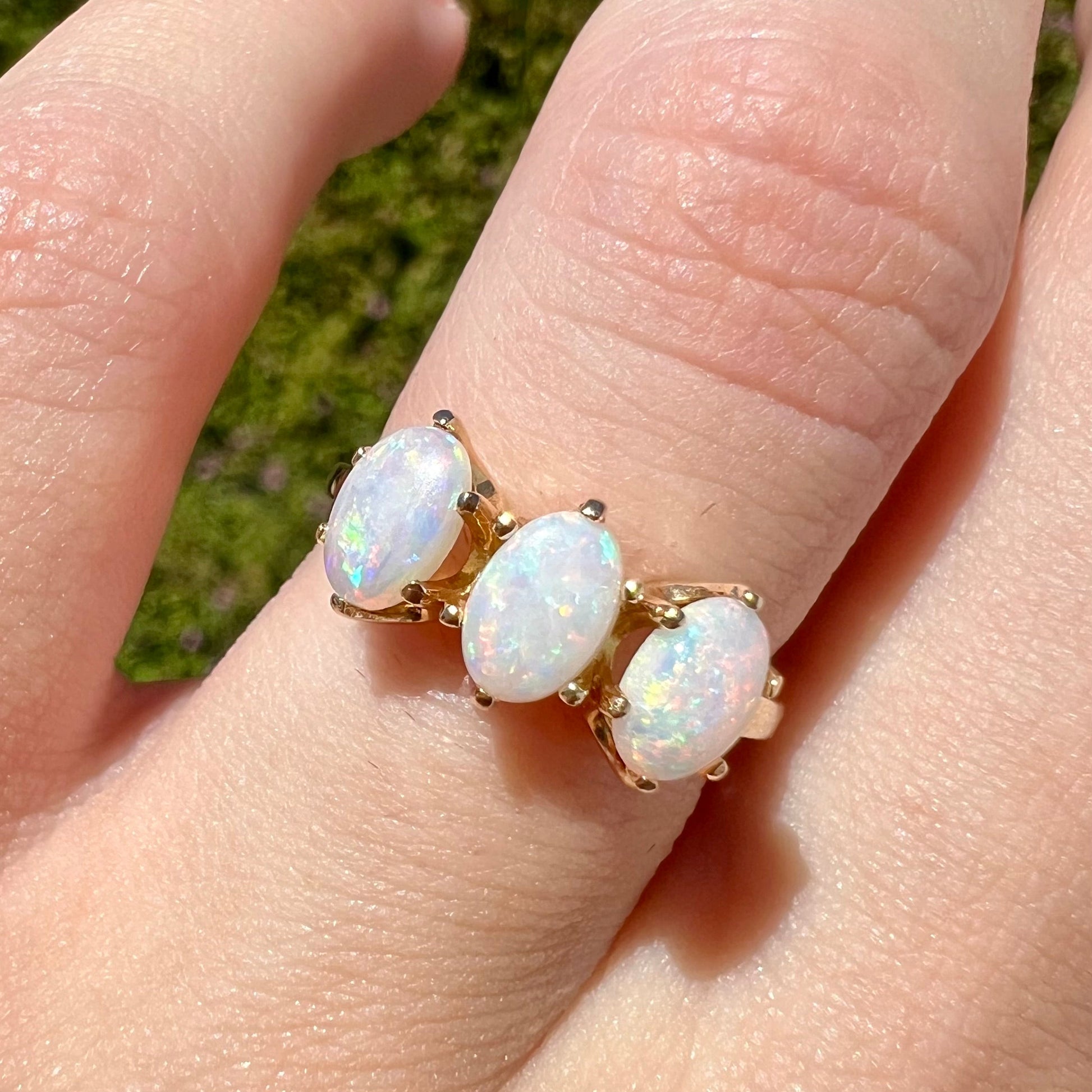 A vintage yellow gold ring mounted with three oval cut white Australian opals.
