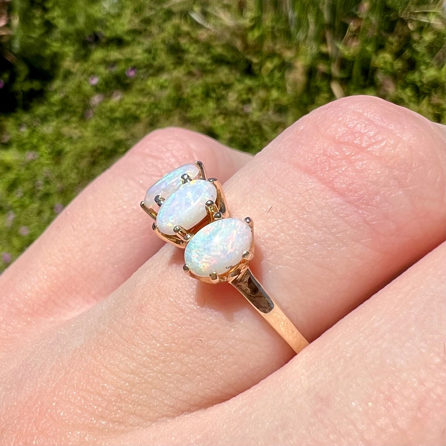 A vintage yellow gold ring mounted with three oval cut white Australian opals.