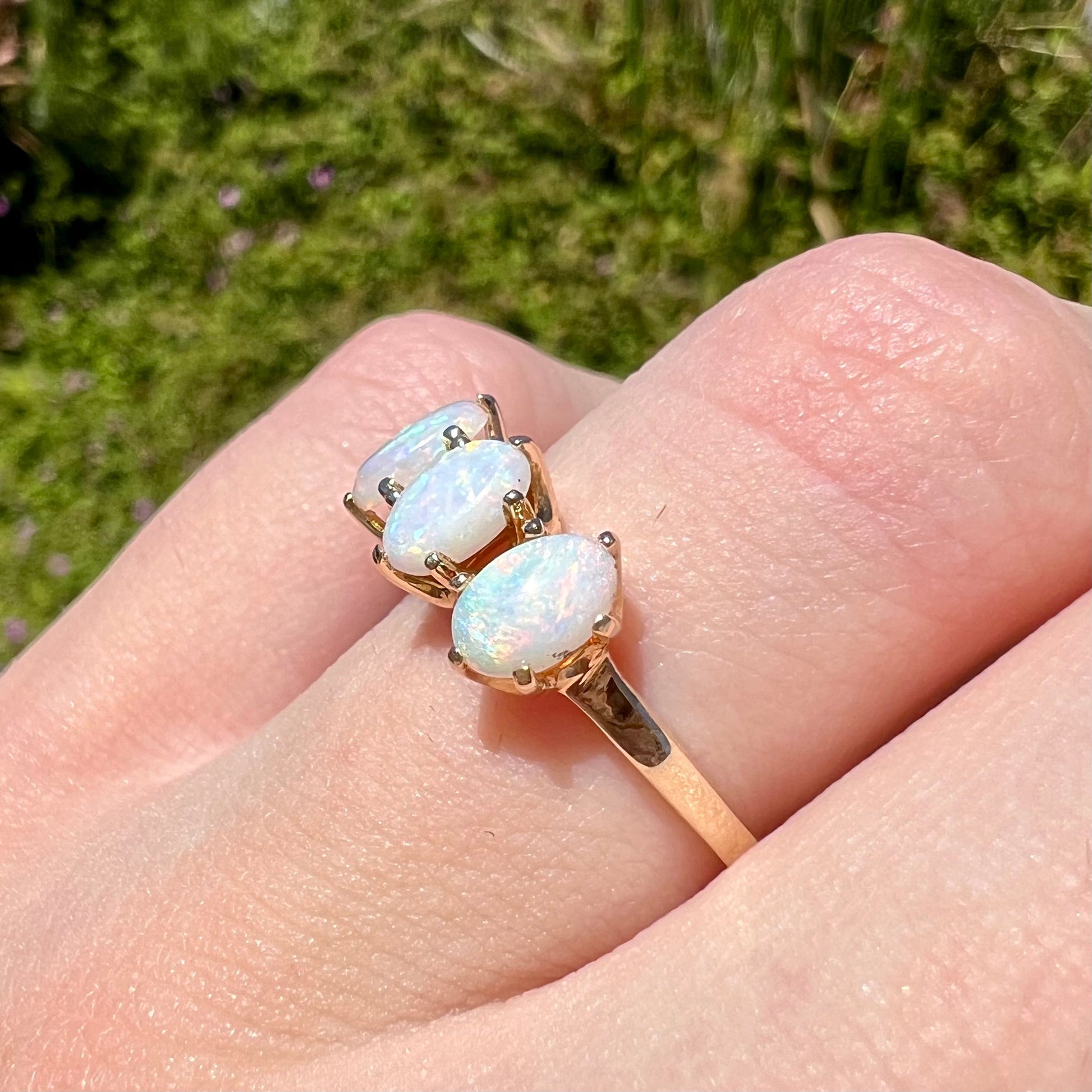 A vintage yellow gold ring mounted with three oval cut white Australian opals.