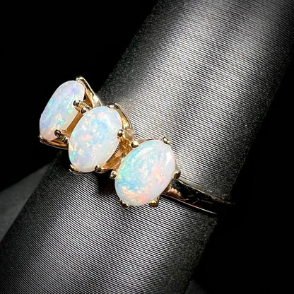 A vintage yellow gold ring mounted with three oval cut white Australian opals.