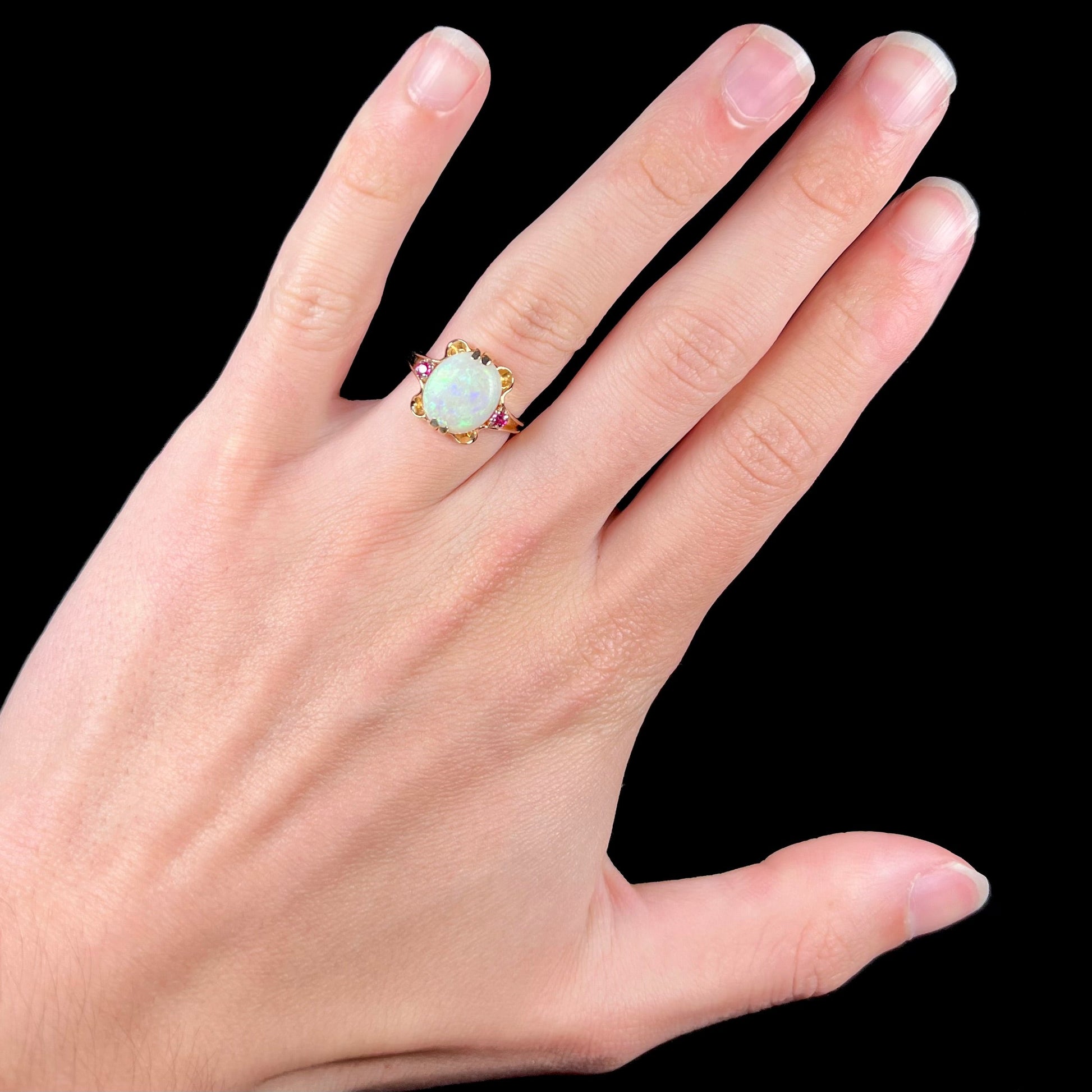 A turn of the century Art Nouveau opal and pink sapphire ring.   The ring is yellow gold and palladium.  The opal is green and purple.
