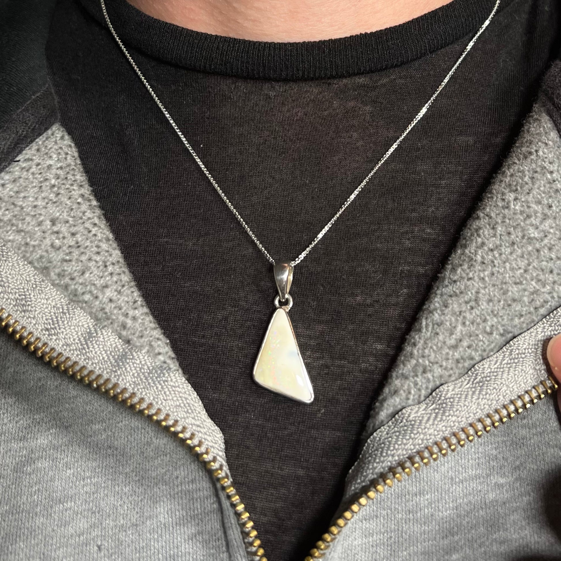 A white Australian boulder opal necklace in .950 silver, worn around a neck against a dark shirt.