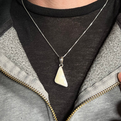 A white Australian boulder opal necklace in .950 silver, worn around a neck against a dark shirt.