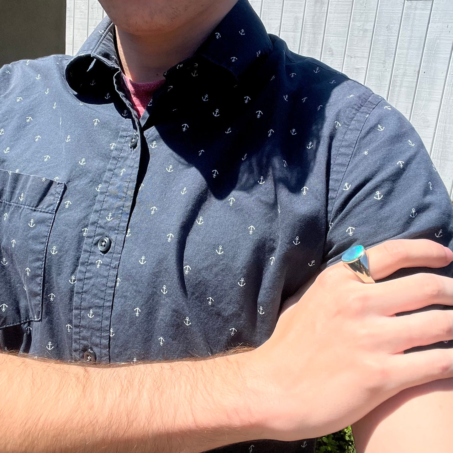 Close-up of person modeling a white gold Australian crystal opal men's ring while resting hand on shoulder in sunlight