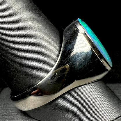 Side view of solid white gold Australian opal men's ring on ring display, focused on ring's heavy shank