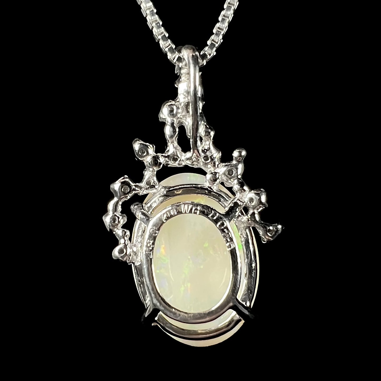 Back view of a white gold opal necklace, showing the openwork basket setting with “K18 WG” and stone weight engraving.