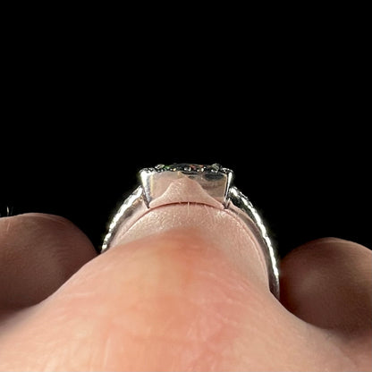 The gallery view of a white gold opal ring, worn on a hand.