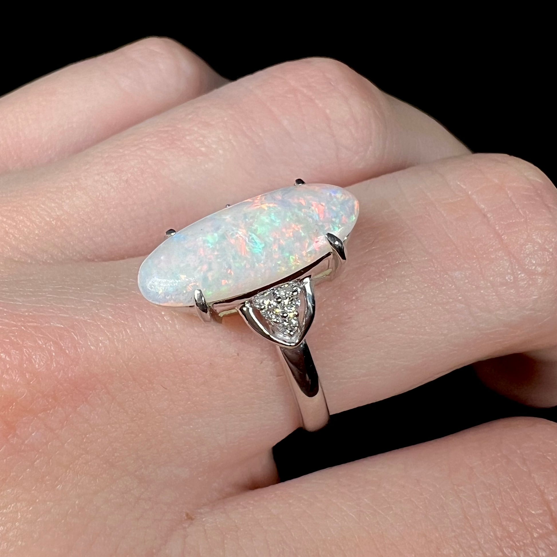 A Coober Pedy white opal platinum ring set with diamond accents.  The opal plays soft pink colors.