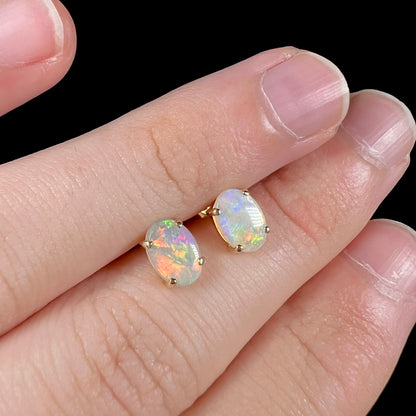 Angled view of opal stud earrings, highlighting a broad red color play in one opal.